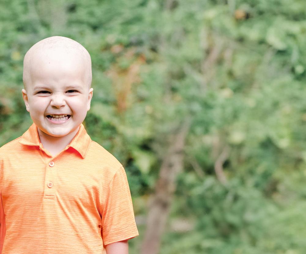 Rally Kid Maddox smiling outdoors in an orange polo